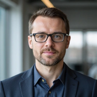 Portrait of Piotr Zieliński, a focused man with glasses, symbolizing a head of research and development.